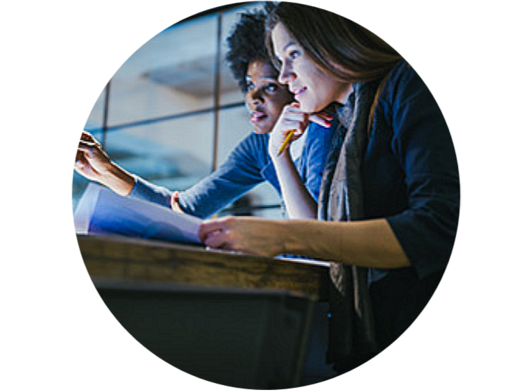 Two lady employees discussing while looking at the monitor