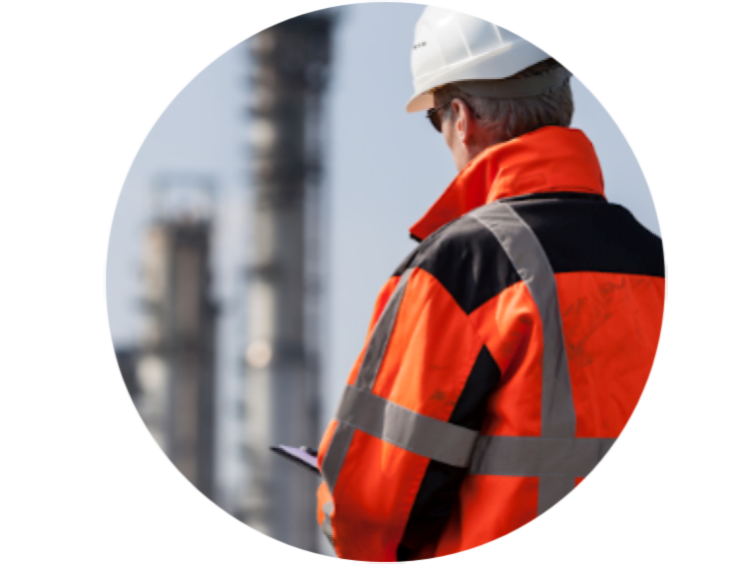 Back view of a manufacturing worker in an orange uniform with a blur background of the manufacturing plant