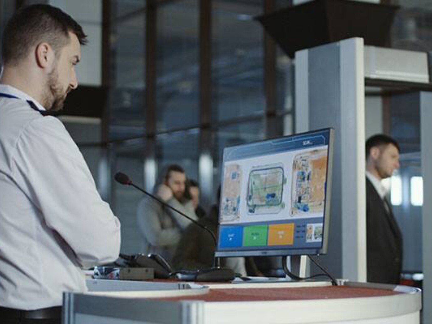 A man stands in front of a computer screen, focused on the display, with a thoughtful expression on his face