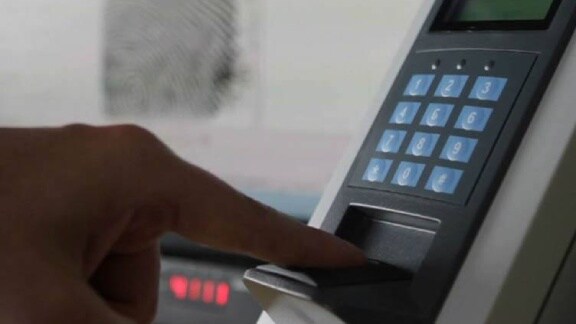 A person is placing their finger on an electronic fingerprint reader for identification purposes
