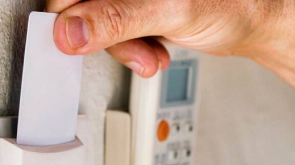 A person holds a card up to a wall-mounted electronic device for access purposes
