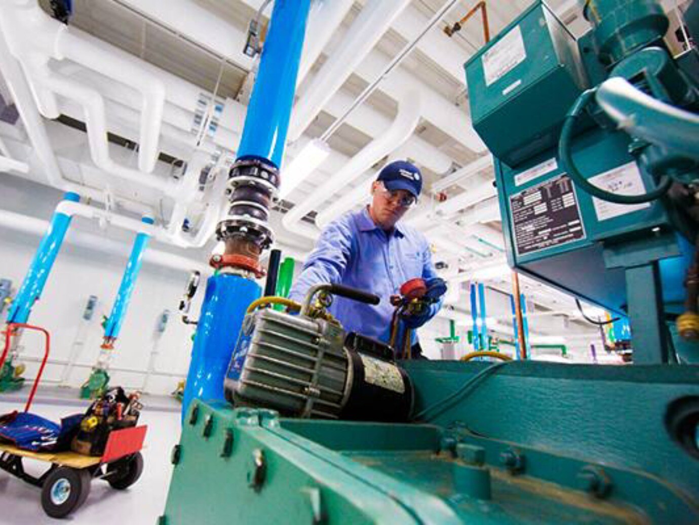 A man wearing a blue shirt and hat is engaged in operating a machine