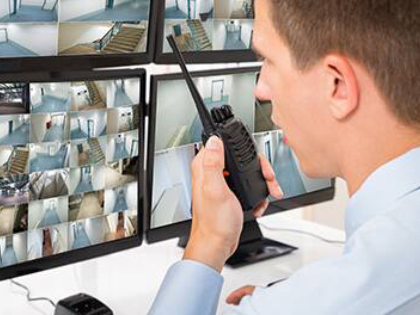 A man communicates with a security camera using a walkie talkie, ensuring surveillance and security measures are in place
