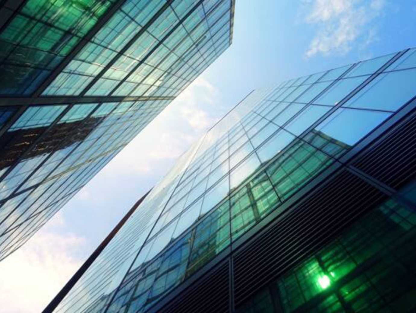 The glass surface of a building mirrors the sky