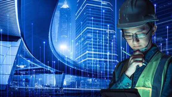 A man in a safety vest is intently reviewing information on a tablet computer at a construction site