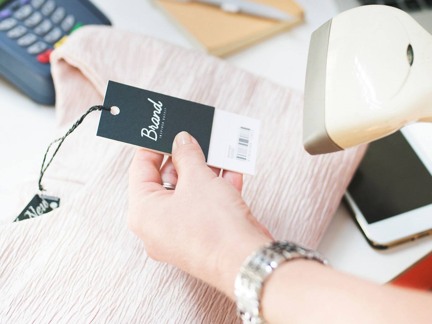 Close-up of a hand holding a credit card alongside a price tag, representing shopping or payment.