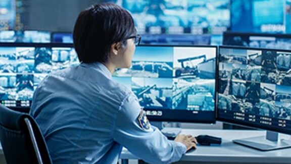 A security personnel closely monitoring the CCTV displays on the monitor