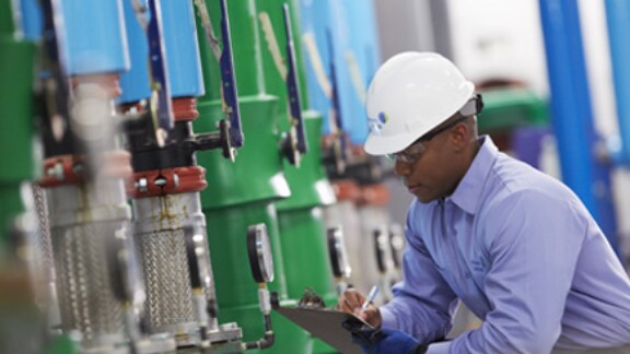A supervisor taking the readings on the floor of a manufacturing unit