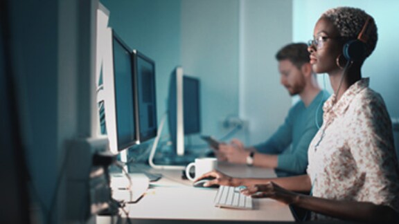 Close up of two employees working on their computers in the office.