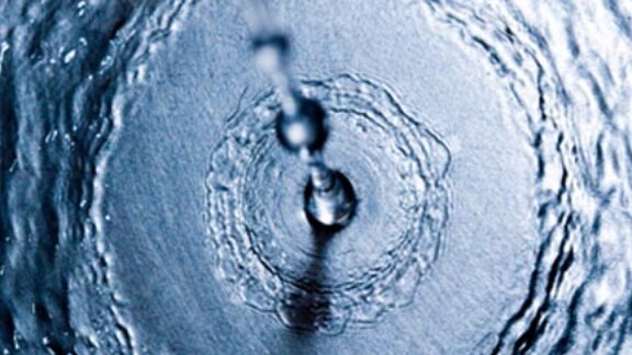 Close up drops of water falling on the ground and creating ripples