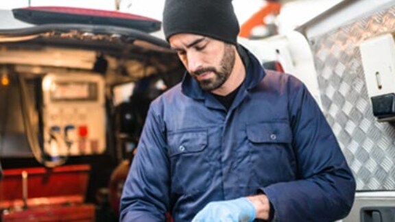 A worker monitoring work on the tab on the floor of a manufacturing facility