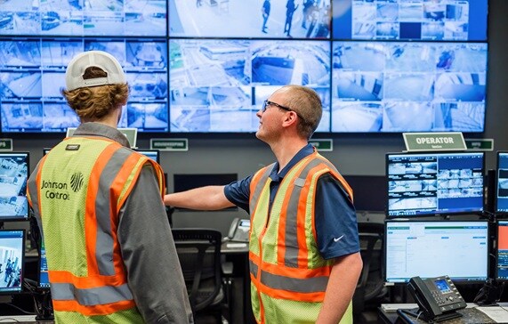An image of two surveillance workers observing cameras on screens