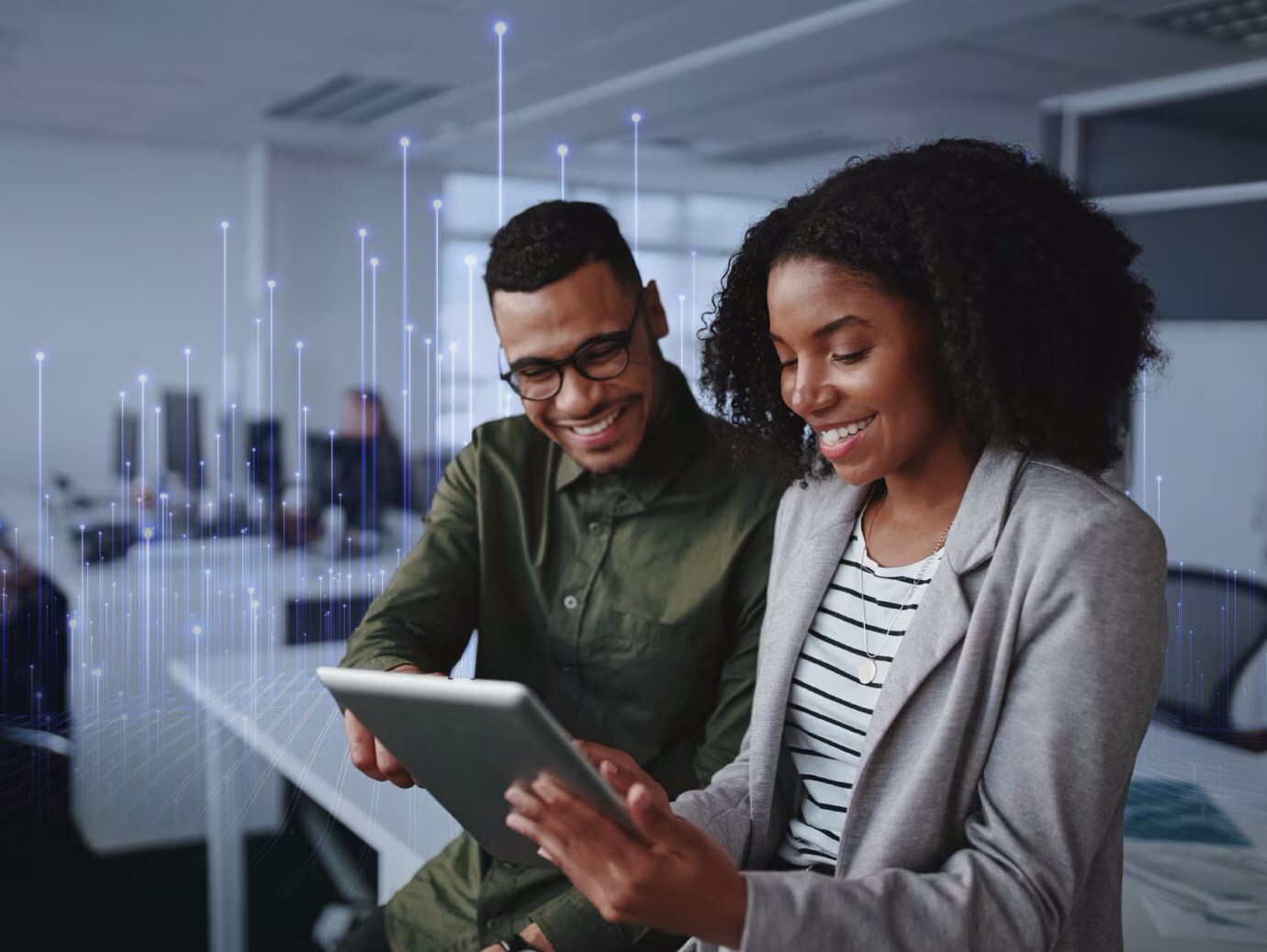 Man and woman using a tablet and having a conversation in office, overlaid with a graphic of transmission nodes